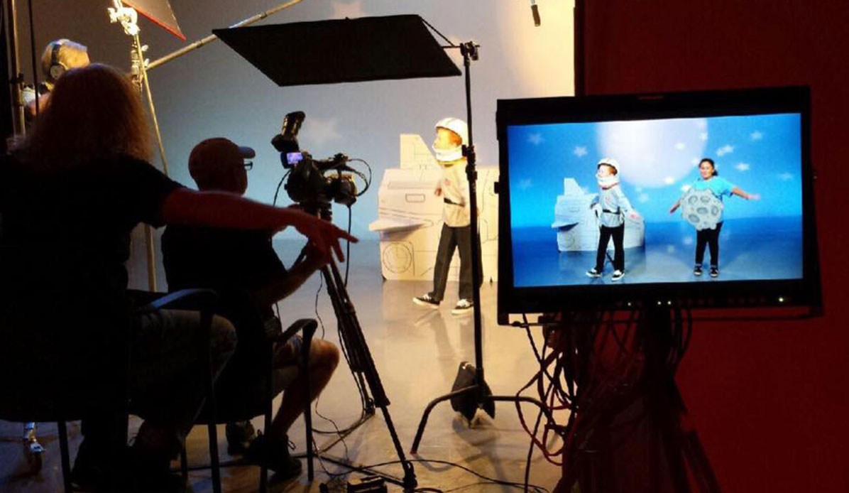 Directors and camera operators watch on a monitor during filming.