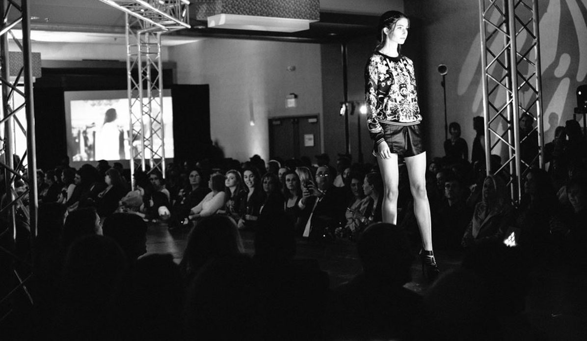 A model stands at the end of the runway in a fashion show.
